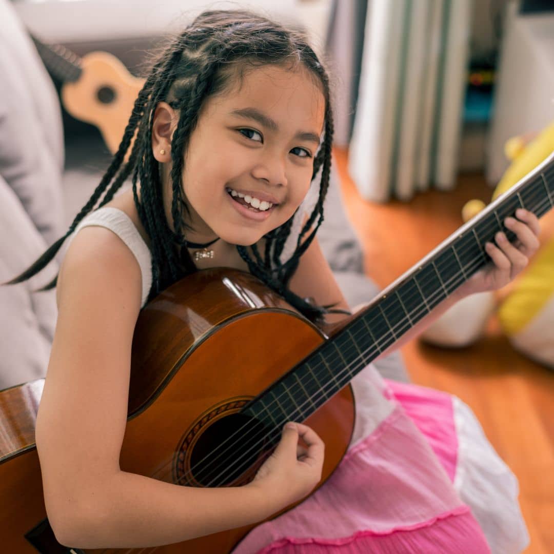 A young girl playing the guitar