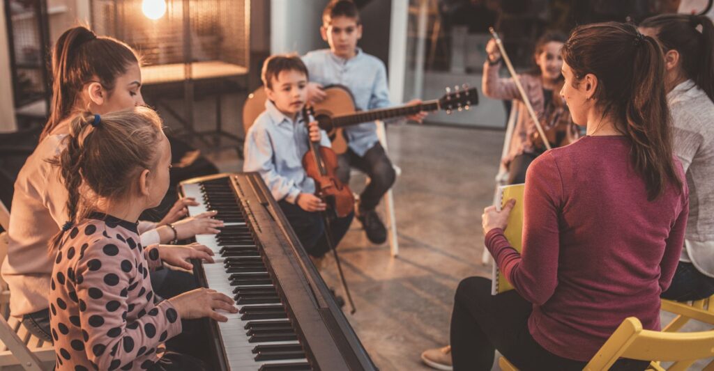 A teacher teaching a music class to young kids.